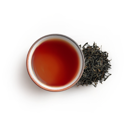Cup of tea with a pile of black tea leaves 